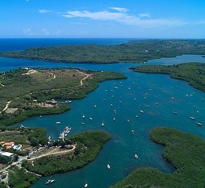 DR-Luperon-Harbour aerial view of a large wide bay with lots of fingers surrounded by green scrubby hills and many boats at anchor within the bays